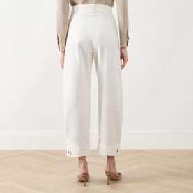 Model wearing Max Mara Main white wide-leg cotton trousers with turn-up cuffs, rear view, styled with beige top and nude heels.