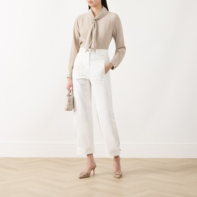 Model wearing Max Mara Main white cotton-blend trousers with wide cropped leg, styled with beige bow blouse and nude heels.