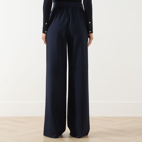 Model wearing Max Mara Main Lira Striped Wide Leg Trousers in ultramarine, wide-leg silhouette, paired with a navy knit top with gold buttons.