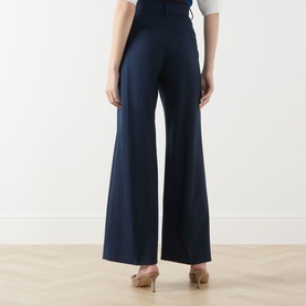 Model wearing Max Mara Weekend navy wide-leg wool trousers, rear view, styled with nude heeled mules