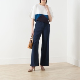 Model wearing Max Mara Weekend navy wide-leg wool trousers, styled with a colour-block top, tan bag and nude heels.