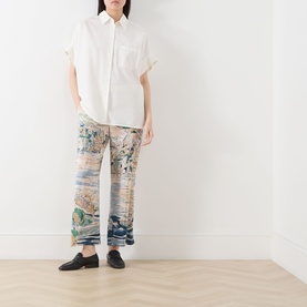 Model wearing Max Mara Weekend light blue silk printed trousers, styled with a white short-sleeve shirt and black loafers.