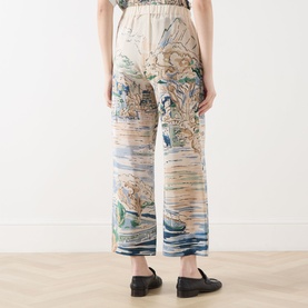Model wearing Max Mara Weekend light blue silk trousers with landscape print, wide-leg cut, elasticated waist. Styled with black loafers.