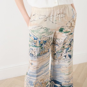 Model wearing Max Mara Weekend light blue silk trousers with scenic coastal print, wide-leg silhouette and elasticated waistband