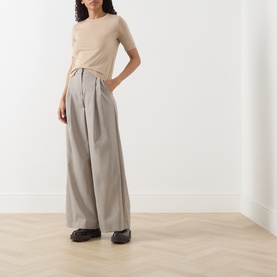 Model wearing Max Mara Weekend hazelnut wide-leg wool trousers with pleated waist, styled with a beige tee and dark chunky loafers.