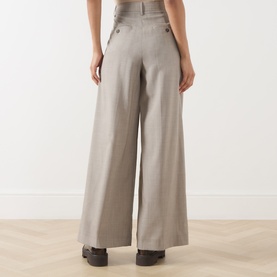 Model wearing Max Mara Weekend hazelnut wide-leg wool trousers, rear view, with decorative button waist detail and dark flat shoes.