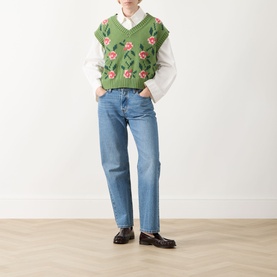 Model wearing Max Mara Weekend Alamaro Floral Knit Vest in green floral with pink roses, styled with white shirt, light blue jeans and dark loafers.