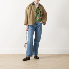 Model wearing Max Mara Weekend Alamaro Floral Knit Vest in Green Floral, styled with tan jacket, light blue jeans and loafers, carrying white bag.