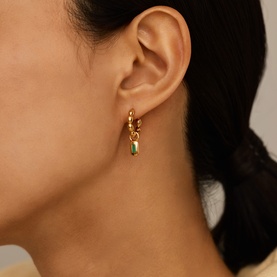 Model with Missoma Gold Olive earrings; gold hoop style with small green stone drop charm, worn on ear