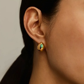 Model with Missoma Gold Olive earrings; chunky gold dome studs with green stone detail