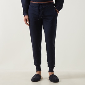 Model wearing Paul Smith Access blue cotton loungewear joggers with drawstring waist and ribbed cuffs, styled with navy slippers
