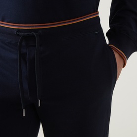 Model wearing Paul Smith Access blue cotton loungewear bottoms with tan stripe waistband trim and drawstring fastening.