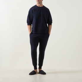 Model wearing Paul Smith Access blue cotton joggers with matching navy sweatshirt and dark slip-on slippers.