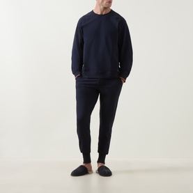 Model wearing Paul Smith Access blue cotton crew neck sweatshirt with matching navy joggers and dark slip-on slippers.