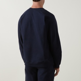 Model wearing Paul Smith Access blue cotton crew neck sweatshirt, shown from the back with striped cuff detail, paired with navy trousers.