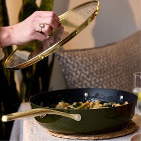 Stellar Cast Light Saut&eacute; Pan 28cm in olive with gold-tone handle and glass lid being lifted, containing cooked greens
