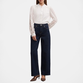 Model wearing Forever New Sutton Embroidered Blouse in Porcelain with broderie sleeves and scalloped trim, styled with dark indigo wide-leg jeans.