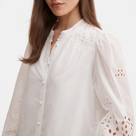 Model wearing Forever New Sutton Embroidered Blouse in Porcelain with broderie anglaise sleeves, stand neckline, and button front fastening.