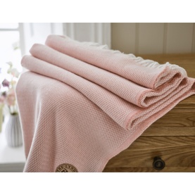 The Lyndon Company Arcadia Throw in Rose, folded on a wooden surface, featuring a textured weave and fringed edges.