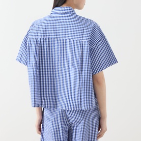 Model wearing American Vintage shirt in Vichy Bleu gingham check, short sleeves, cropped fit, styled with matching trousers, back view