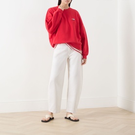 Model wearing American Vintage red cotton sweat top, styled with white wide-leg trousers and black sandals.