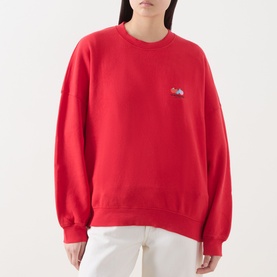 Model wearing American Vintage red cotton crew neck sweat top with small chest logo, styled with white jeans