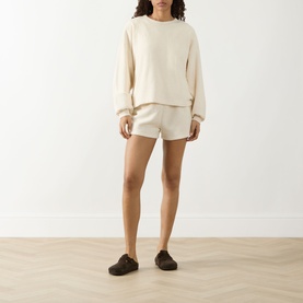 Model wearing American Vintage Bobypark Ecru Textured Sweatshirt with matching ecru shorts and dark slip-on shoes.