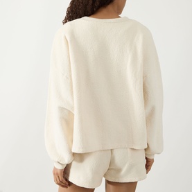 Model wearing AMERICAN VINTAGE Bobypark Textured Sweatshirt in Ecru, back view, styled with matching shorts. Dropped shoulders, long sleeves.