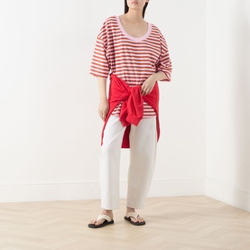 Model wearing American Vintage T-Shirt in Rayures Bonbon red and white stripe, styled with white trousers, red tied shirt and black sandals