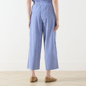 Model wearing AMERICAN VINTAGE trousers in Vichy Bleu gingham cotton, wide-leg cropped cut, rear view, styled with tan flat mules.