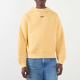 Model wearing About:Blank Arc Logo Hoodie in yellow with small red logo, kangaroo pocket, styled with blue jeans.