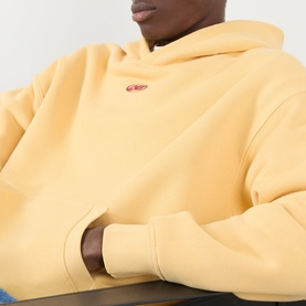 Model wearing About:Blank Arc Logo Hoodie in yellow, featuring small red logo at chest, fixed hood and dropped shoulders.