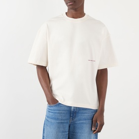 Model wearing About:Blank Oblique Logo T-Shirt in oat, relaxed fit with small logo print, styled with light blue jeans.