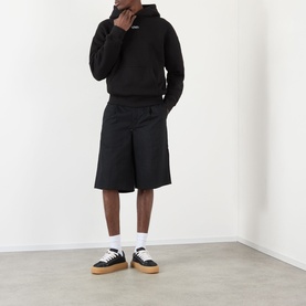 Model wearing About:Blank Arc Logo Hoodie in black with wide-leg black shorts and black and gum-sole trainers with white socks.