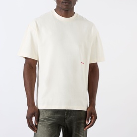 Model wearing About:Blank Haus Logo T-Shirt in oat/red, relaxed fit with dropped shoulders and small red logo print, styled with grey jeans