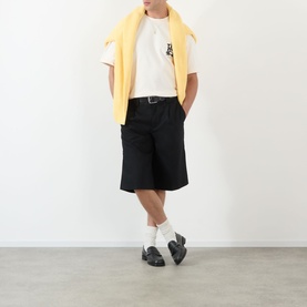 Model wearing About:Blank oat cotton T-shirt, styled with black shorts, yellow jumper over shoulders, white socks and black loafers.