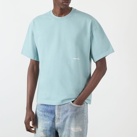 Model wearing About:Blank Box Logo T-Shirt in tourmaline, crew neck, short sleeves, small chest logo, styled with distressed blue jeans.