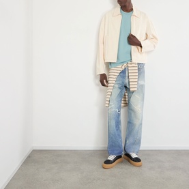 Model wearing About:Blank Box Logo T-Shirt in tourmaline/ecru, styled with cream jacket, light wash distressed jeans and black flatform trainers.