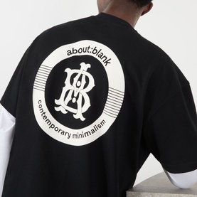 Model wearing About:Blank black cotton T-shirt, back view showing circular logo graphic with monogram and "contemporary minimalism" text.