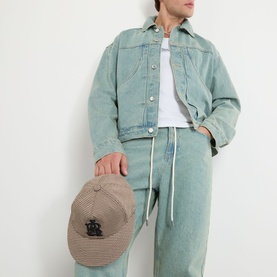 Model wearing About:Blank murky wash cotton casual jacket, styled with matching wide-leg jeans and white tee, holding a beige cap.