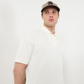 Model wearing cream short-sleeve polo shirt with zip collar, styled with a beige cap