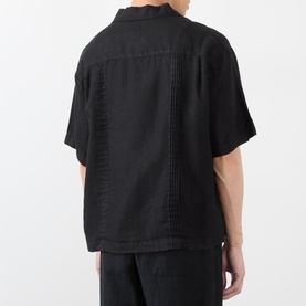 Model wearing black short-sleeve shirt with pintuck pleat back detail, styled with matching black trousers