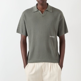 Model wearing About:Blank Logo Open-Knit Polo Sweater in sage, open-knit cotton with V-neck collar and contrast logo, styled with cream trousers