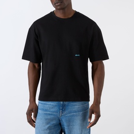 Model wearing About:Blank Box Logo T-Shirt in black, featuring dropped shoulders and small logo print, styled with blue jeans.