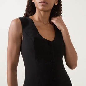 Model wearing Anne Louise Boutique black sleeveless dress with scoop neckline and button-front detail, close-up crop view.