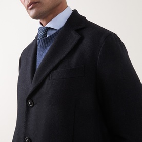 Model wearing Boglioli navy wool coat, styled with blue knit sweater and dotted tie, single-breasted with notch lapels