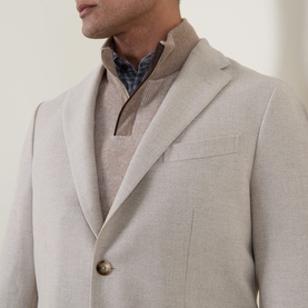 Model wearing Boglioli beige wool blend jacket with notch lapels and gold buttons, styled with a brown knit half-zip and check shirt underneath.