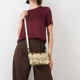 Model carrying Mario Valentino Sleet Sequin Crossbody Bag in yellow sequins, gold-tone hardware, worn on adjustable strap across body.
