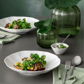 Villeroy & Boch Pura Bowl in white bone porcelain, styled with salad and greens on a grey table with ribbed green glass vase