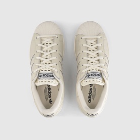 Adidas off-white canvas low-top trainers, overhead view showing lace-up front, Three Stripes detail and contrast dark heel tab.
